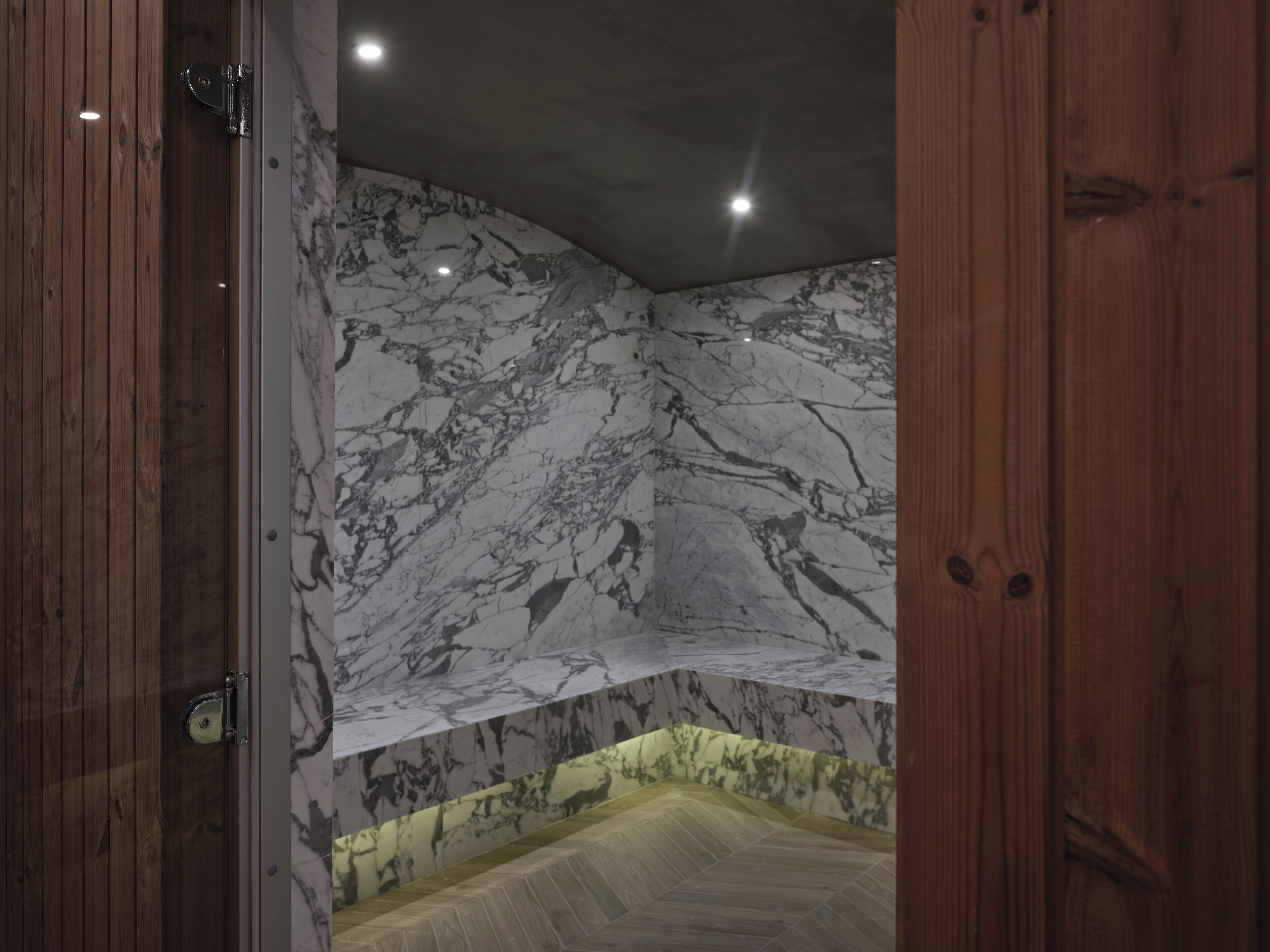 A corner of a room with marble walls and a wooden floor.
