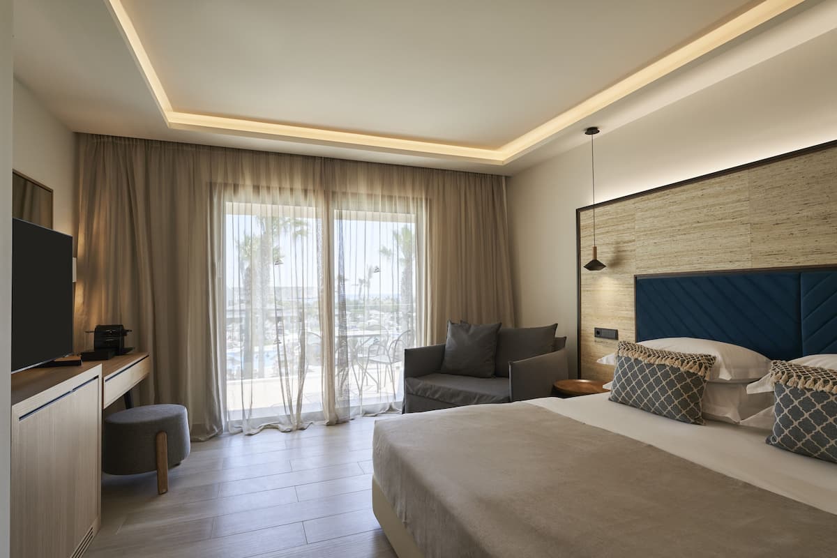 A modern hotel room with a bed, a desk, a chair, and a TV.