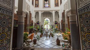 A spacious interior with a tiled floor, ornate columns, and a central fountain. - Riad Norma (Fes)