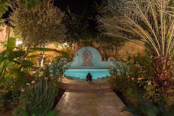 Una piscina al aire libre, sombrillas, sillones reclinables de piscina