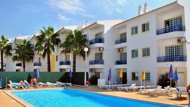 A hotel with a swimming pool, sun loungers, and palm trees. - Sereia da Oura (Albufeira)