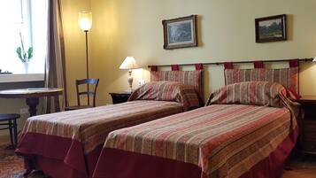 Une chambre avec deux lits, une chaise, une petite table et deux lampes.