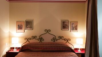 Una habitación de hotel con una cama con dosel, dos mesitas de noche con lámparas y tres cuadros enmarcados en la pared.