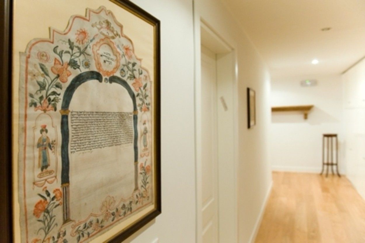 Een gang met een lijstwerk kunstwerk aan de muur, een houten vloer en een deur aan het einde.