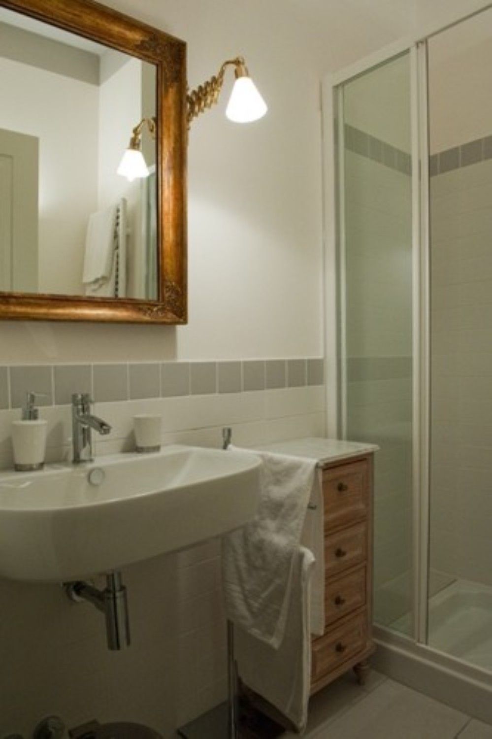 Une salle de bain avec un grand miroir, un lavabo, un porte-serviettes et un espace douche.