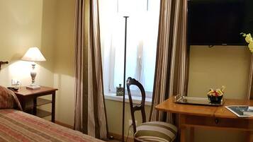 Habitación de hotel con dos camas, un escritorio, una silla, un televisor y una ventana con cortinas.