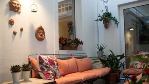 A cozy outdoor seating area with a cushioned bench, potted plants, and wall-mounted decorations. - Residenza Le 6 A (Trieste)