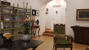 A room with a green bookshelf, a wooden chair, a fireplace, and a framed picture on the wall. - Residenza Le 6 A (Trieste)
