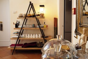 A room with a wooden shelf unit displaying various items, a tripod lamp, and a wooden mannequin. - Residenza Gens Julia (Rome)