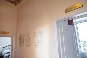 A room with a bed, a door, and three wall-mounted plaques. - Residenza Gens Julia (Rome)