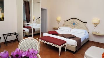 Habitación de hotel con una cama grande, dos lámparas de noche, un espejo, una mesita y una silla.