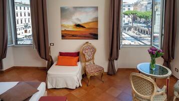 Une chambre d’hôtel avec un lit, une chaise, une table et un tableau au mur.