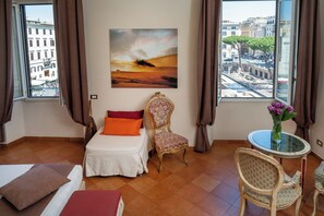 Una camera d'albergo con un letto, una sedia, un tavolo e un quadro appeso al muro.