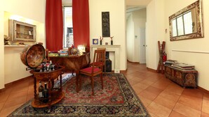 A room with a wooden dining table, a red chair, a globe, and a patterned rug. - Residenza Gens Julia (Rome)