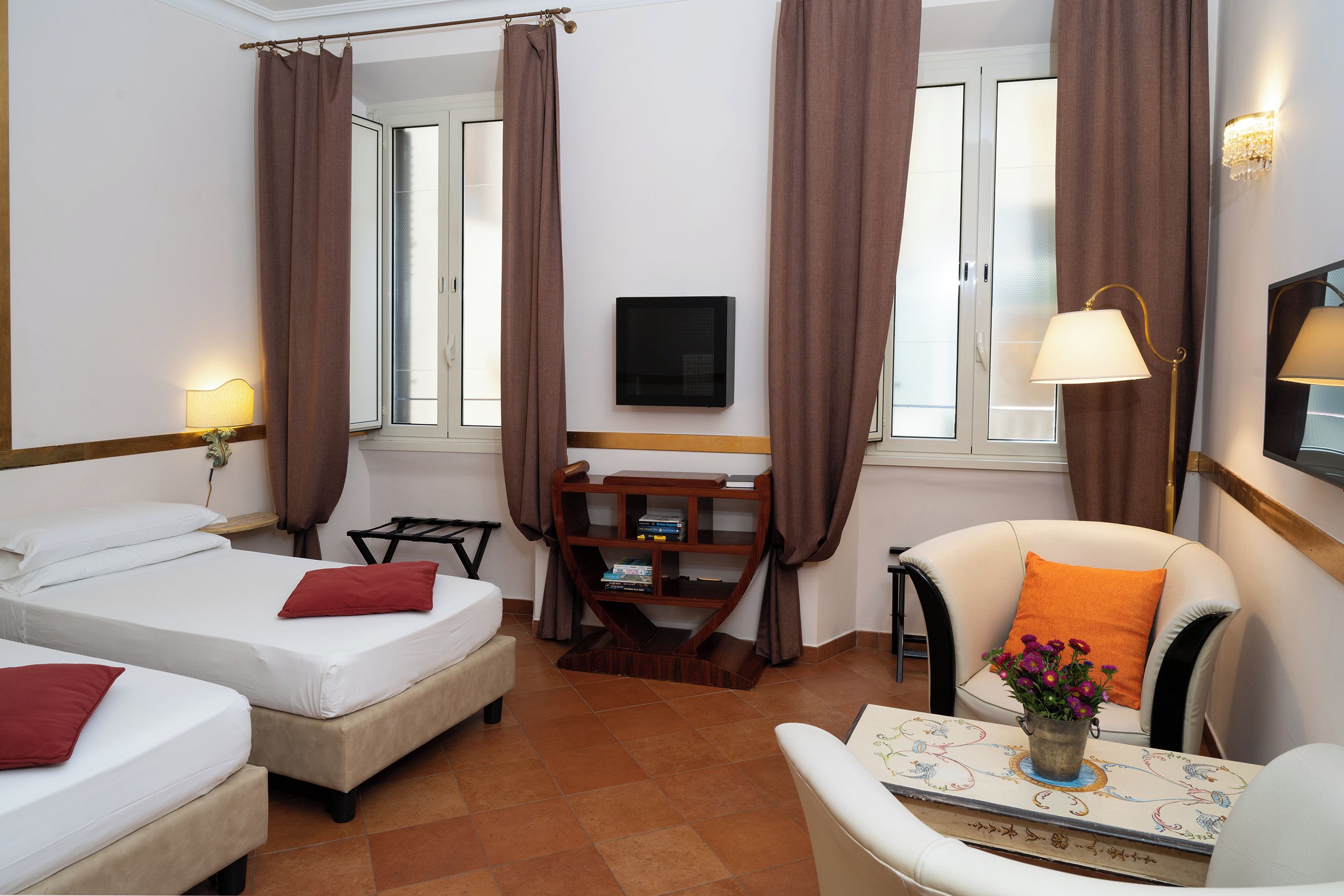 Een hotelkamer met twee bedden, een bureau met stoel, een televisie en een raam met gordijnen.