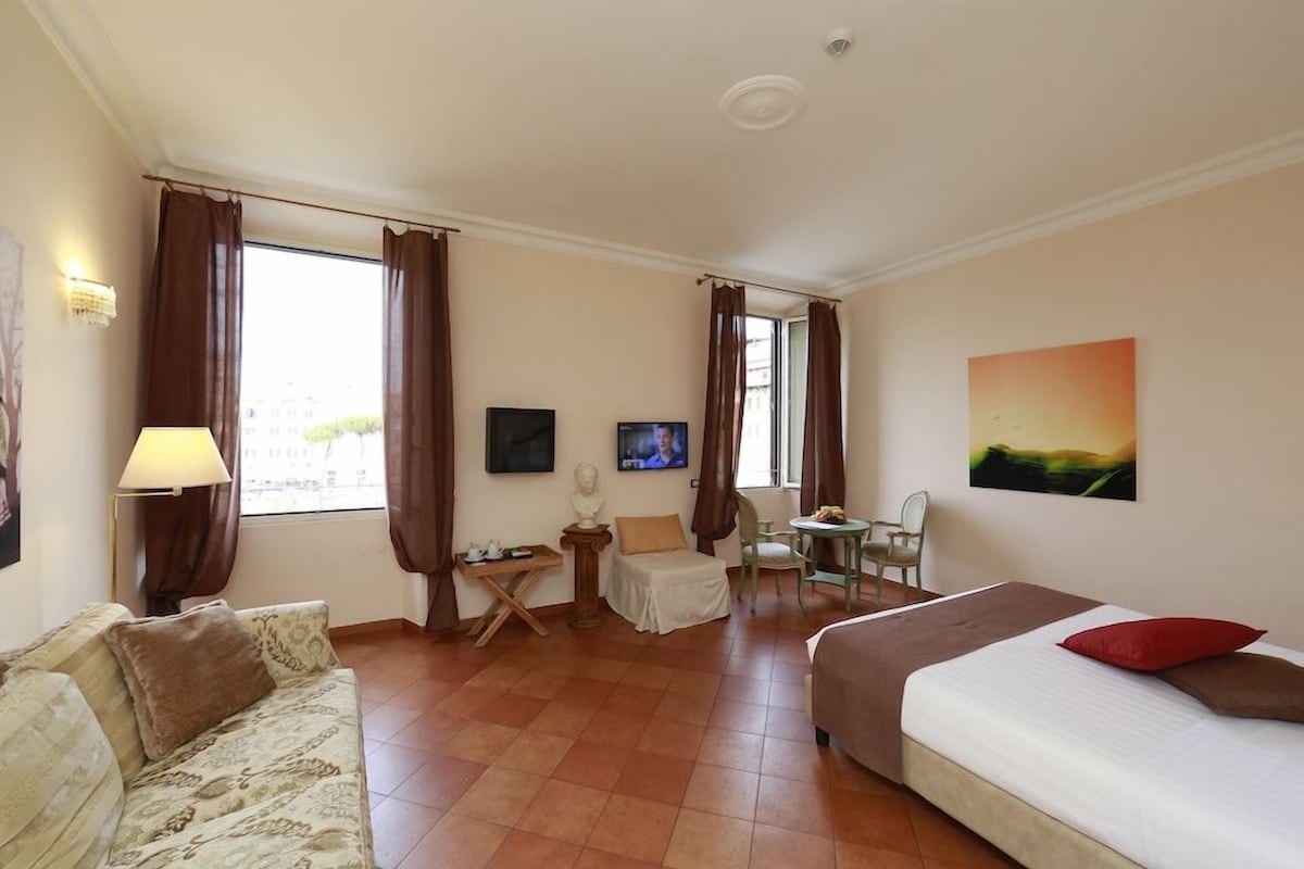 Una habitación de hotel con una cama, un sofá, un escritorio, una silla y un televisor.
