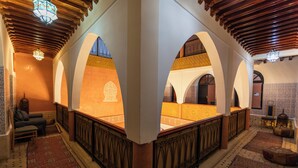 Um interior tradicional com arcos, tapetes estampados e teto de madeira.