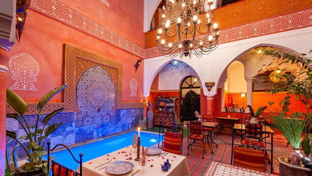 Área de refeições com piscina, decoração elaborada e um lustre.