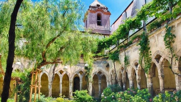 A courtyard with stone arches, a bell tower, and lush greenery. - Villa Fernanda (Massa Lubrense)