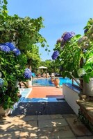 Zona de piscina con vista despejada, rodeada de exuberante follaje e hidrangeas azules.