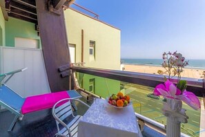 A balcony with a table, a chair, and a view of the beach.