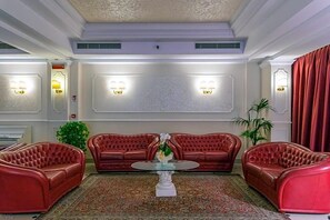 A room with a red leather sofa set, a glass coffee table, and a patterned rug. - La Fiorita (Rimini)