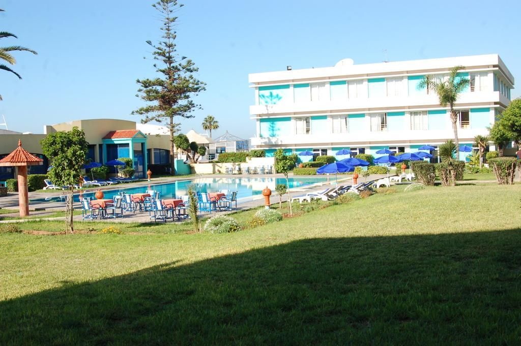 A hotel with a swimming pool, sun loungers, and umbrellas.