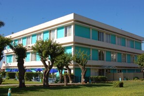 A multi-story hotel with a flat facade, large windows, and a well-maintained lawn with trees and umbrellas. - Mabrouk Hotel and Suites- Adult Only (Agadir)