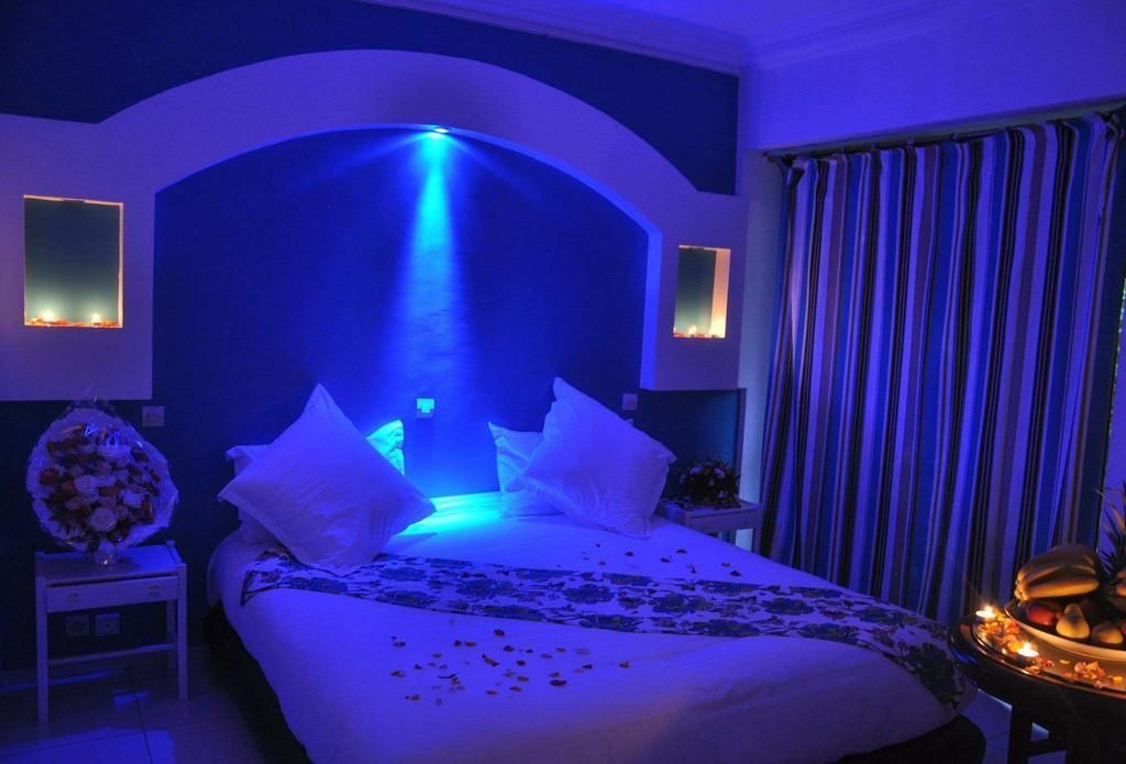 A hotel room with a bed, a nightstand, a vase of flowers, and a curtain.