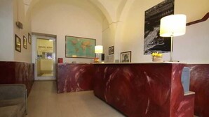 Una zona de recepción con mostrador de mármol, cuadros enmarcados y un mapa en la pared.