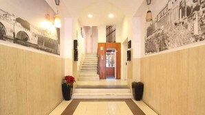 A hotel lobby with a staircase, wooden panel walls, and a tiled floor. - Romalive Hotel (Rome)