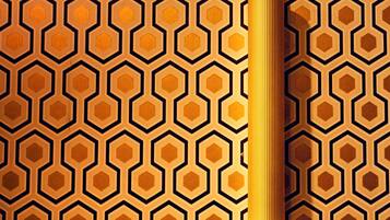 A wall with a geometric pattern of hexagons and a cylindrical object, possibly a lamp, on the right side.