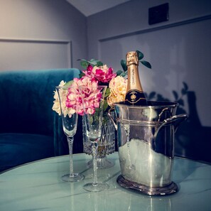 A table with a champagne bottle, a metal bucket, and two glasses with flowers. - The Ferryman (Dublin)