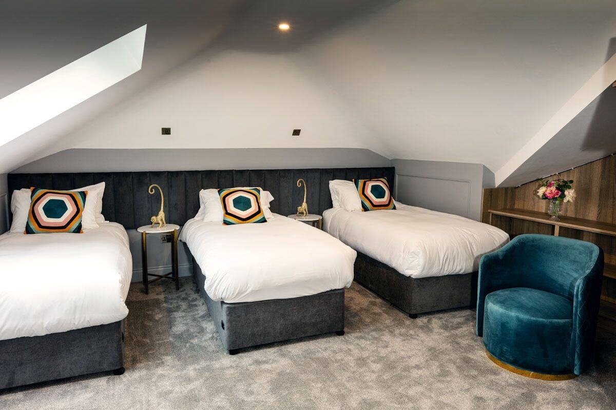 A modern bedroom with three beds, a small table, and a blue chair.