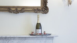A fireplace with a marble mantle, a framed mirror above it, and a wall-mounted light fixture. - Caroline Suite (Rome)