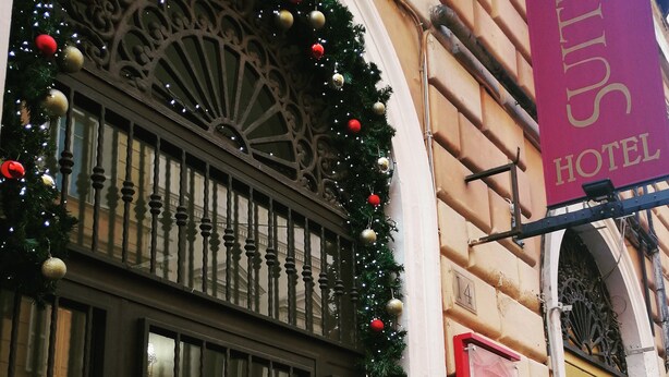A hotel entrance with a decorative archway, a sign reading "SUITE CAESAR HOTEL", and a number "4" above the door. - Caroline Suite (Rome)
