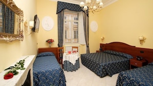 A hotel room with two single beds, a wooden headboard, a table with a vase of flowers, a chair, and a mirror with an ornate frame. - Caroline Suite (Rome)