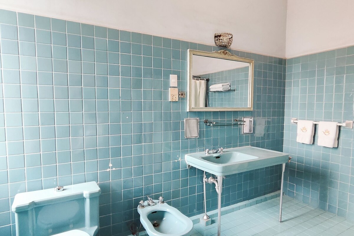 A bathroom with a toilet, bidet, and sink, all with a blue tiled wall and floor.