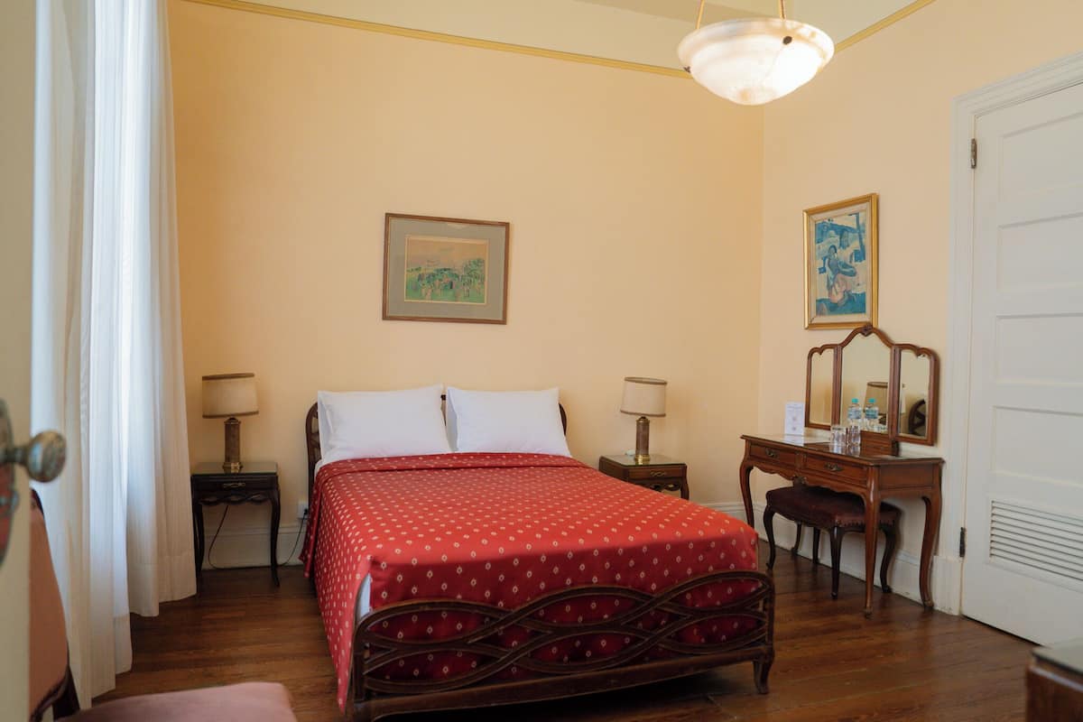 A bedroom with a bed, bedside tables, a desk, and a chair.