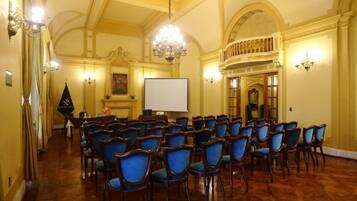 Una sala de conferències amb files de cadires, una pantalla de projector i un lampadari.