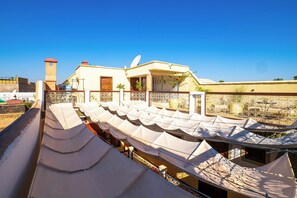 An outdoor seating area with rows of white canopies and a building with a satellite dish in the background. - Riad Chalymar (Marrakech)