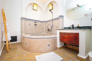 Un baño con bañera, una escalera de madera, un espejo y suelo de baldosas.