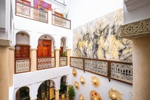 A courtyard with a white building featuring wooden doors and balconies with wrought iron railings. - Riad Chalymar (Marrakech)