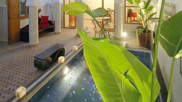 Una stanza con piscina, un divano rosso e un'area pranzo.
