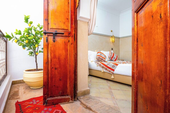 A room with a bed, a potted plant, and a wooden door.