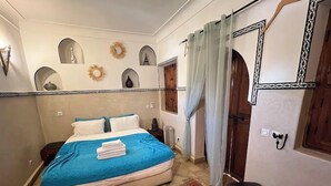 Una camera da letto con un letto, un comodino, un tappeto rosso e una panca in legno.