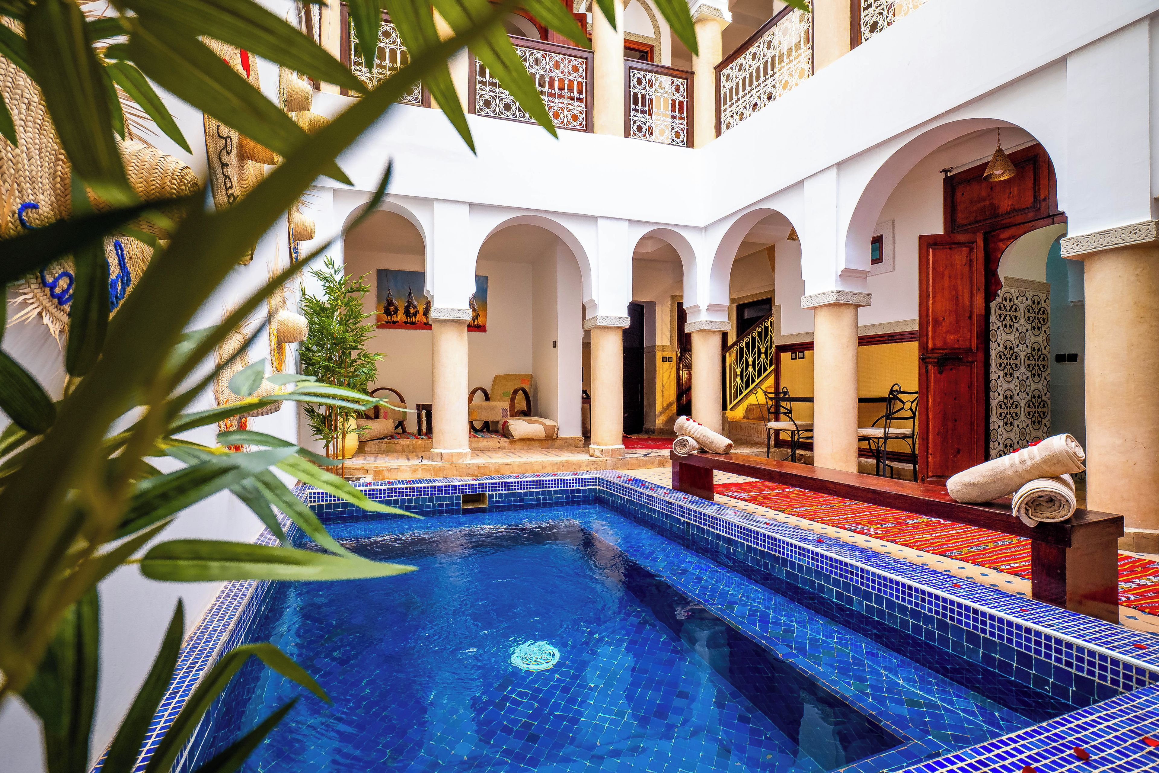 A pool area with a tiled floor, a wooden bench, and a door with a patterned design.