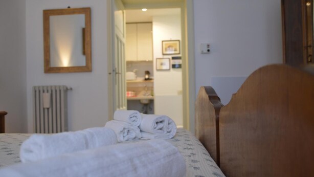A bedroom with a bed, a wooden headboard, a mirror, and a radiator. - A Casa Cibella (Rome)