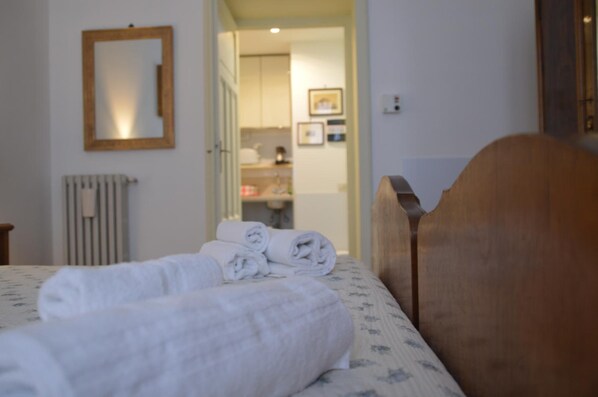 A bedroom with a bed, a wooden headboard, a mirror, and a radiator. - A Casa Cibella (Rome)