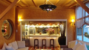 A cozy room with a bar area, wicker furniture, and a large mirror. - Hotel Cerro da Marina (Albufeira)